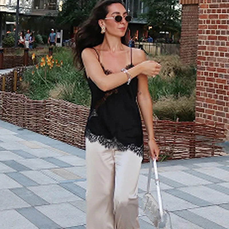 Woman wearing HXAO asymmetrical slip top women with sunglasses and stylish pants in a park setting.