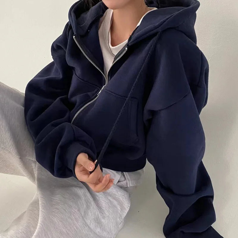 Cropped zip-up sweatshirt in navy worn with light gray pants, showcasing a relaxed casual style.