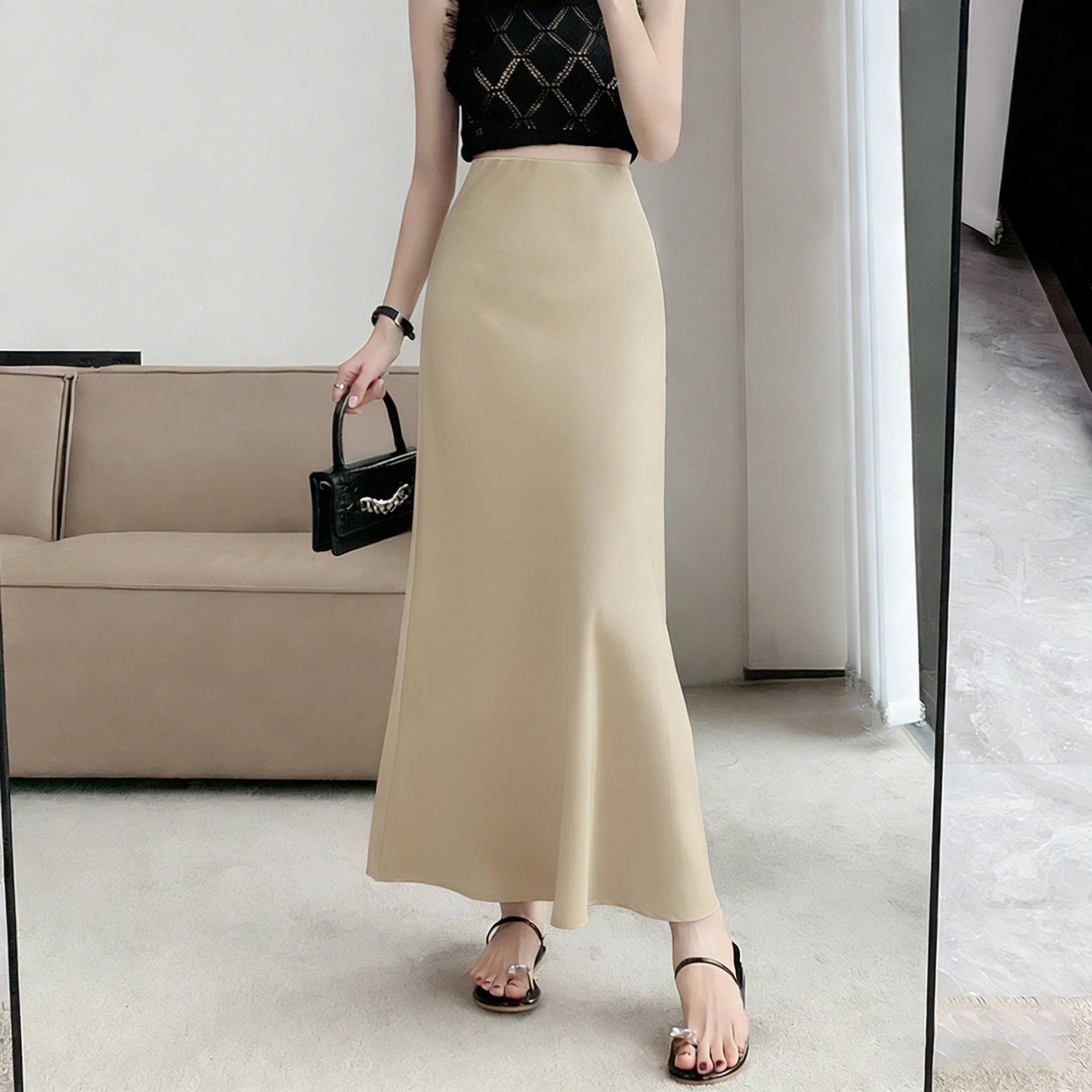 Stylish model showcasing an acetic satin fishtail skirt, paired with a black top and accessories, in modern interior setting.
