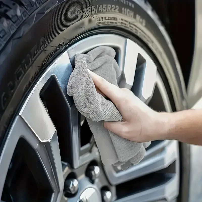 Person using microfiber cleaning cloths to clean a car tire and rim for a spotless finish.