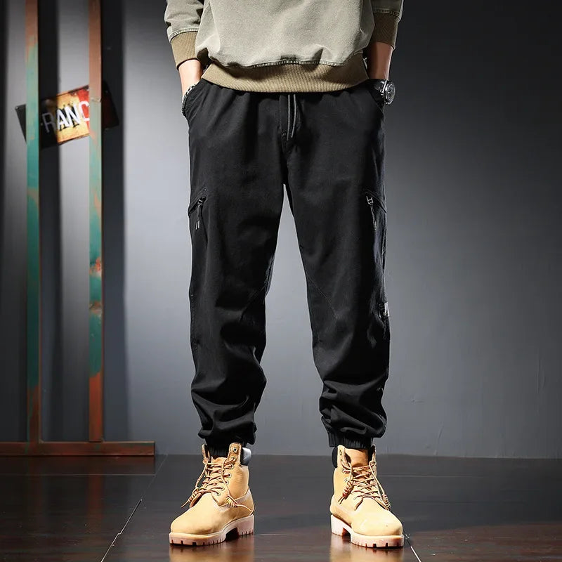 Stylish man wearing cargo trousers for men, black cargo pants paired with casual boots and a sweatshirt.
