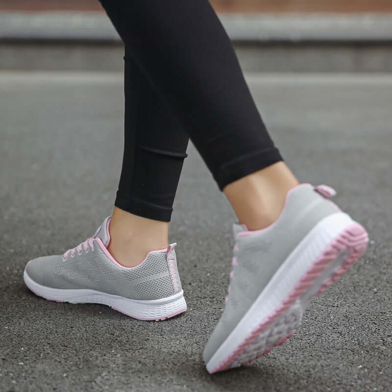 lightweight women's sports sneakers in gray and pink worn by a woman during outdoor activity